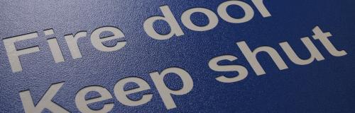 Rond gegraveerd blauw kunststof bord met witte waarschuwingstekst voor brandwerende deuren